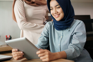 portrait of beautiful muslim woman who is very happy to see the results of her efforts on tablet at office