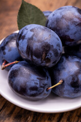 heap of a purple damsons plums over grunge wooden background. natural fruits. healthy eating concept