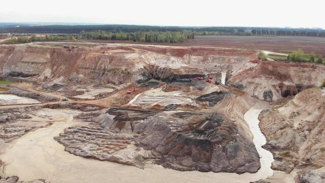 Opencast mining quarry with lots of machinery. Iron ore quarry from bird's eye view. Open pit for gold mining. Open pit mine coal mining, dumpers, quarrying extractive industry stripping work