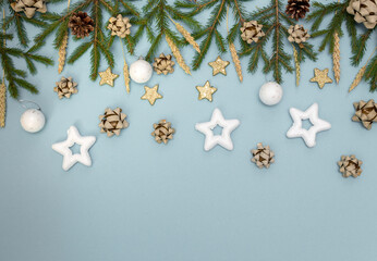 Green Christmas tree branches with New year's toys. Cones, bows and Gold stars on a sky-blue...
