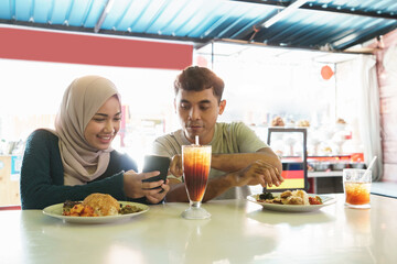 the couple is eating traditional food while looking at the phone