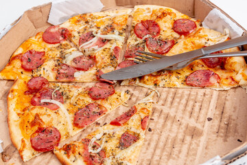 Round pepperoni pizza with fork and knife on it.