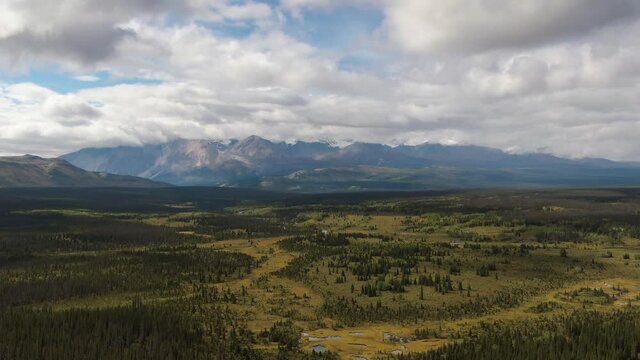Beautiful View of Lush Forests, Trees and Land surrounded by Mountains on a Cloudy Summer Day in Canadian Nature. Aerial Drone Shot. Taken near Alaska Highway, Yukon, Canada.