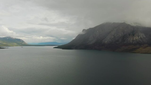 Beautiful Panoramic View of Lake surrounded by Mountains and Trees on a Cloudy Day. Aerial Drone Shot. Southern Yukon, Canada.