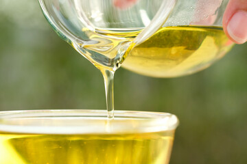 Pouring olive oil in the a glass bowl at stone kitchen and inside green garden view. Prepare for cooking concept. Healthcare and Beauty Concept.