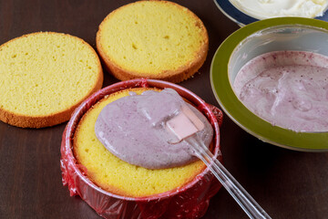 Making festive cake with purple and white cream.