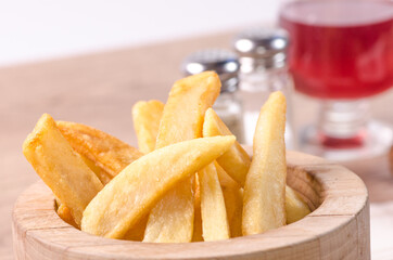 Close up of french fries in wooden bowl.