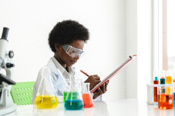 African american cute little boy student child learning research and doing a chemical experiment while making analyzing and mixing  liquid in glass at science class on the table.Education