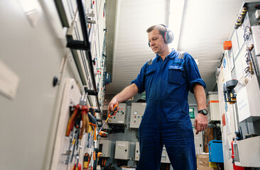 Marine engineer officer in engine control room ECR. He works in workshop and chooses correct tools and equipment
