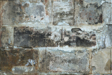 An old wall of gray blocks lined up in even rows. Texture.