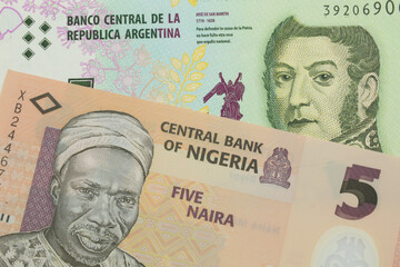 Fototapeta na wymiar A macro image of a orange, plastic five naira note from Nigeria paired up with a colorful five peso note from Argentina. Shot close up in macro.