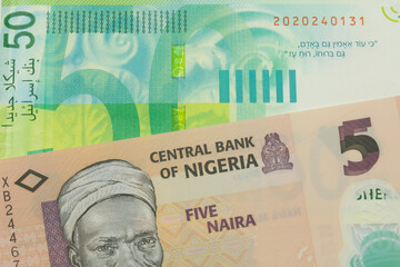 A macro image of a orange, plastic five naira note from Nigeria paired up with a green and white fifty shekel bank note from Israel.  Shot close up in macro.