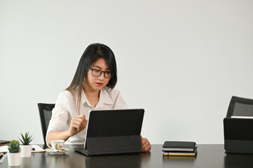 Young female entrepreneur working on mock up tablet while sitting at comfortable workspace.