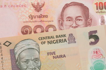 A macro image of a orange, plastic five naira note from Nigeria paired up with a red, one hundred...