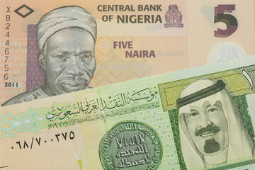 A macro image of a orange, plastic five naira note from Nigeria paired up with a green and yellow on riyal bank note from Saudi Arabia.  Shot close up in macro.