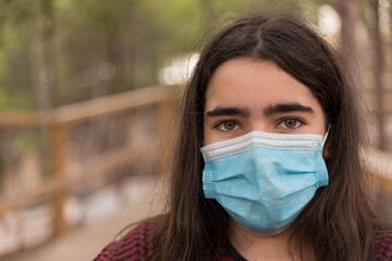 Close-up portrait of a teenager with long hair and protective mask in the field.