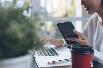 Young asian business woman working and surfing the internet on laptop computer and using mobile...