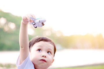 Cute little boy flying his toy plane in nature at sunset. The pilot is that dream in the future of...
