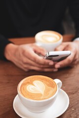 drinkinking coffee an using phone