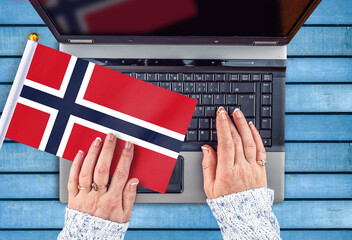 woman hands and flag of Norway on computer, laptop keyboard 