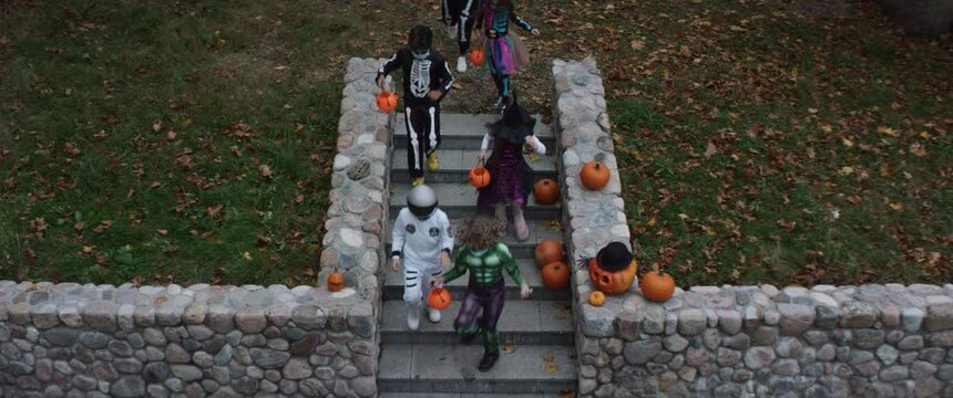 HIGH ANGLE Group of trick-or-treating kids walking down the stairs. Shot on RED Cinema camera with 2x Anamorphic lens