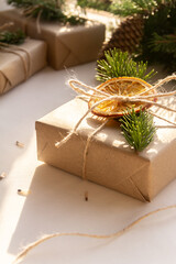 Christmas composition of a Christmas tree with cones, Christmas gifts in craft packaging, slices of dried orange on a white background