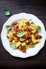 Ravioli with mushrooms and fresh basil. Dark wooden background. Top view.
