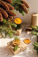 Christmas composition of a Christmas tree with cones, Christmas gifts in craft packaging, slices of dried orange on a white background