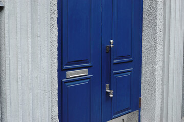 Blue wooden door with moldings, door handle and built-in postal box.
