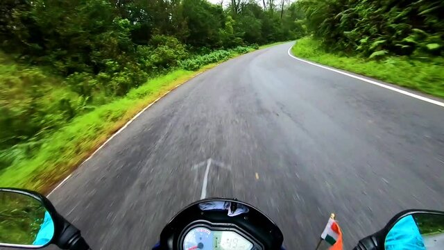 motorcycle ridding at twisty mountain road with lush green forests