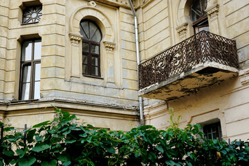 Old building facade. Architectural details: arch windows, decorative columns, open forged balcony.