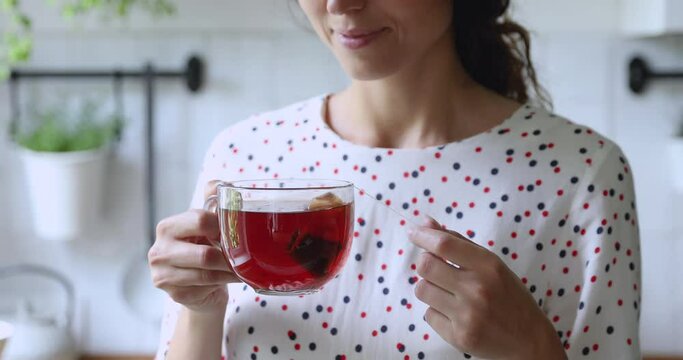 Woman holding mug with hot fresh brewed black teabag tea make sip smiles standing alone in kitchen close up view. Pleasant ritual, enjoy favorite drink while daydream in morning, start new day concept