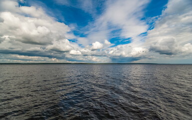 Summer landscape with a wide river, a strip of the opposite Bank and a blue sky with white clouds