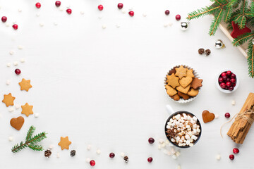Christmas decoration, cup of coffee, homemade sweet gingerbread cookies, pine cones and branches on white wooden background.