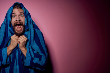 Bearded man in a blue striped robe on a pink background with hands emotions model portrait