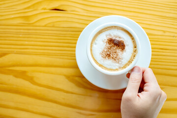 Top view of hot cappuccino coffee on wooden table background. Copy space. 