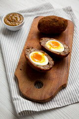 Homemade Scotch Eggs on a rustic wooden board, low angle view.
