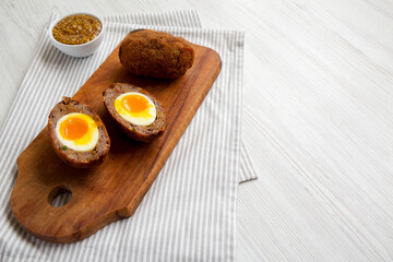 Homemade Scotch Eggs on a rustic wooden board, side view. Space for text.