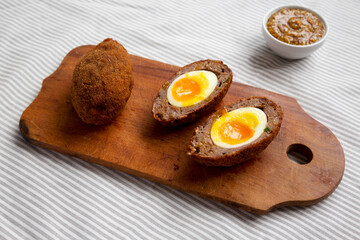 Homemade Scotch Eggs on a rustic wooden board, side view.