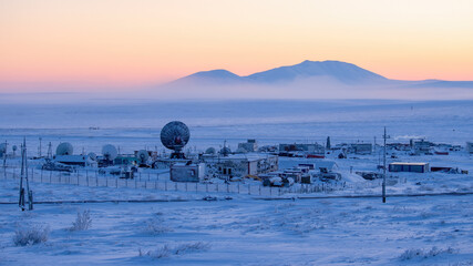 Winter Arctic industrial landscape. Large satellite dishes in the snow-covered tundra. Telecommunications in the Far North of Russia. Cold weather. Northern climate of Chukotka and polar Siberia.