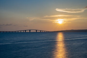 Fototapeta na wymiar 海辺で眺める沈む夕日と橋、宮古島・トゥリバーサンセットビーチ