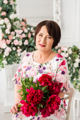 Beautiful senior woman at home with a bouquet of flowers. Happy Mother's Day. Beauty, fashion. Happy retirement.