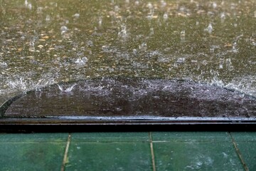 Heavy rain drops hit the rug in front of the front door