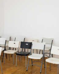 black chair in the group of white chairs in a neutral studio space