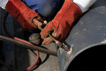 Welder worker welding a wide metal pipe tube with a oxy-fuel cutting torch