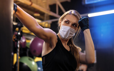 Pandemic gym - woman working out with protective face mask during coronavirus outbreak