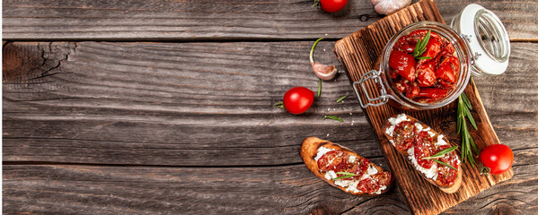 sandwich with goat cheese, sun-dried tomatoes and garlic, oregano, olive oil wooden textured background. space for text. top view. Long banner format