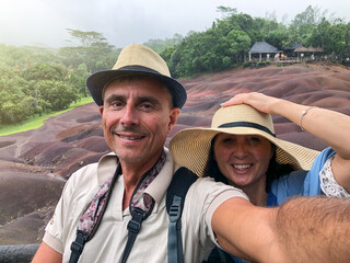 Happy couple wearing hats and smiling in a tropical island excursion with rain