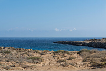 Fototapeta na wymiar Rocky beach of Mediterranean Sea near the Cavo Greco cape on Cyprus, Agia Napa. Bright sunny day with cloudless sky