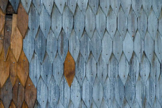 Repair of a house wall. Replacement of wedge-shaped shingles with new ones. Wooden shingle also known as gont in Ukraine.  Copy space.